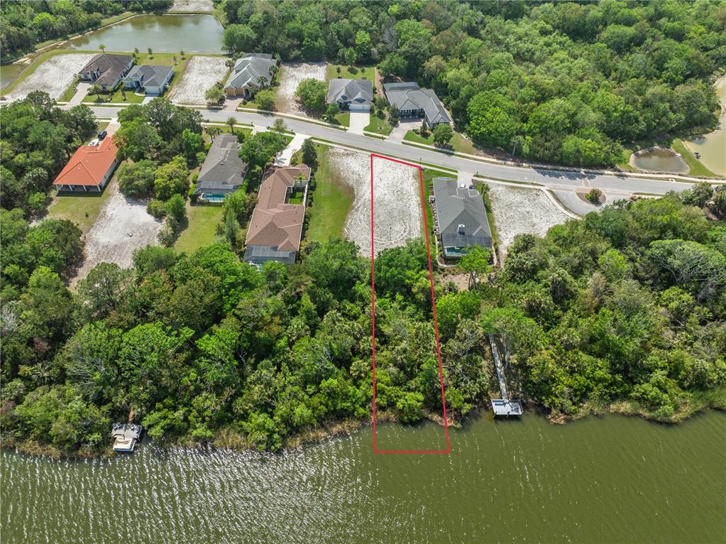 An aerial view shows a vacant waterfront lot outlined in red next to a house — 48 N LAKEWALK DRIVE, PALM COAST, FL