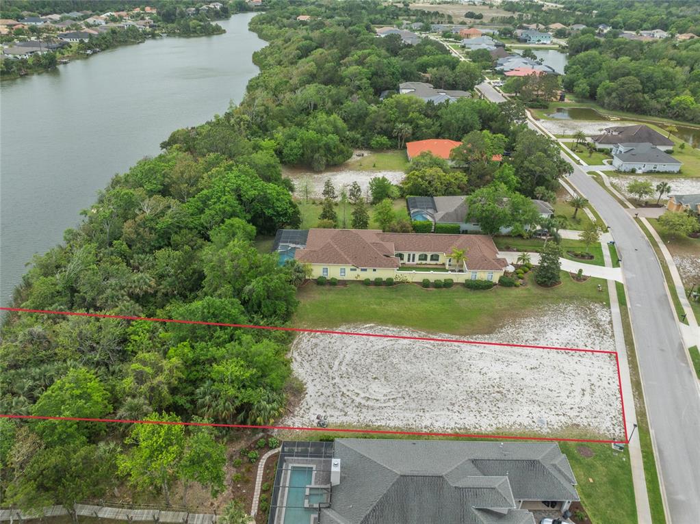 An aerial view shows a vacant residential lot outlined in red between two existing houses — 48 N LAKEWALK DRIVE, PALM COAST, FL