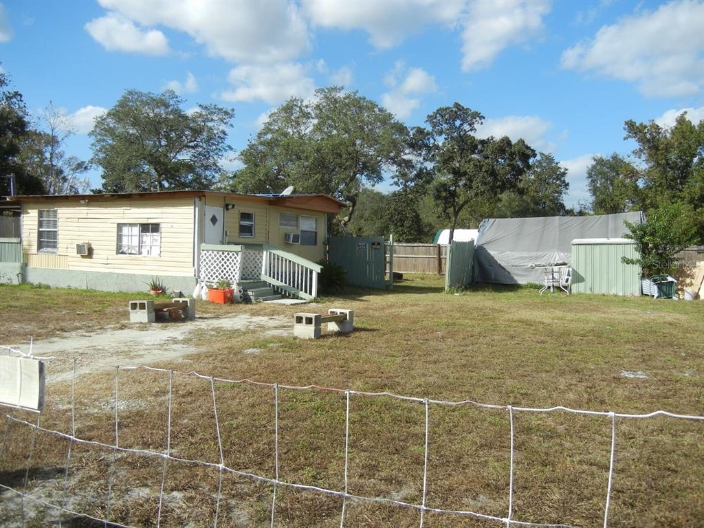 A single-story mobile home with a small porch sits on a large, grassy lot — 27945 VEVA AVENUE, PAISLEY, FL