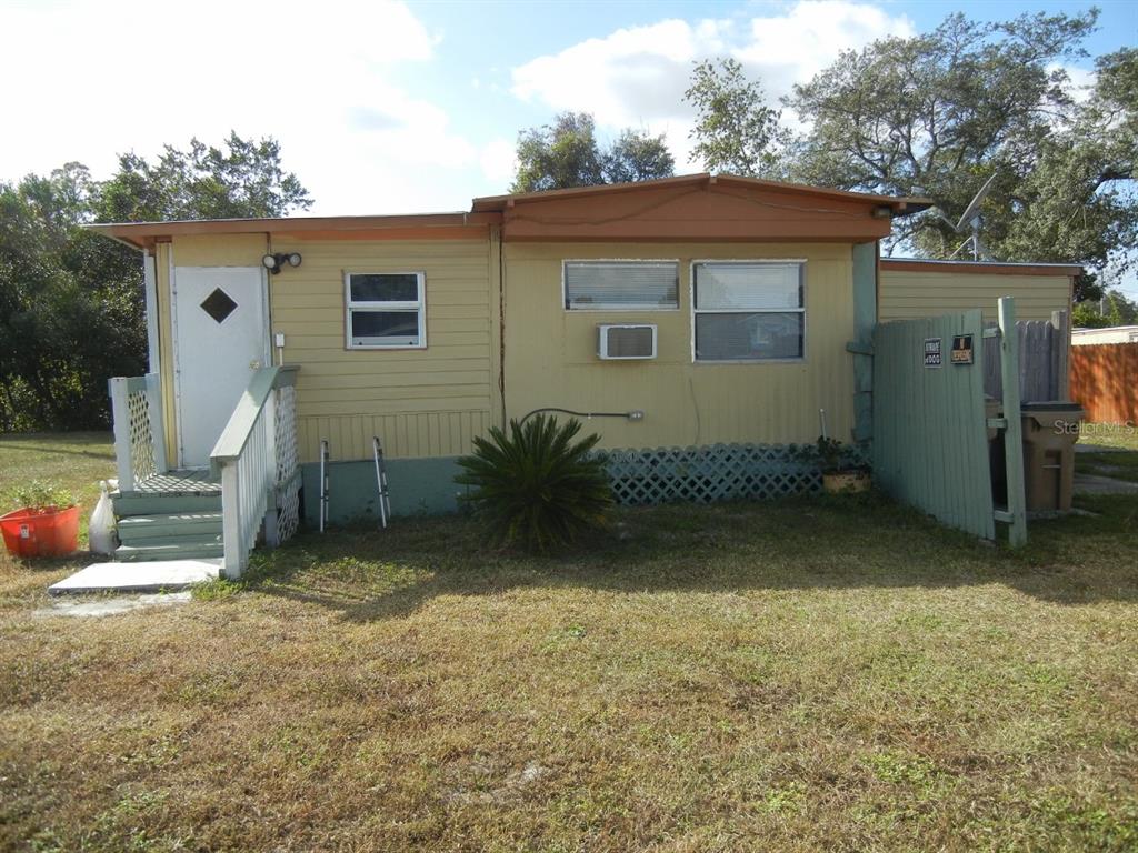 A single-story mobile home with yellow siding, a white front door, and a wooden staircase — 27945 VEVA AVENUE, PAISLEY, FL