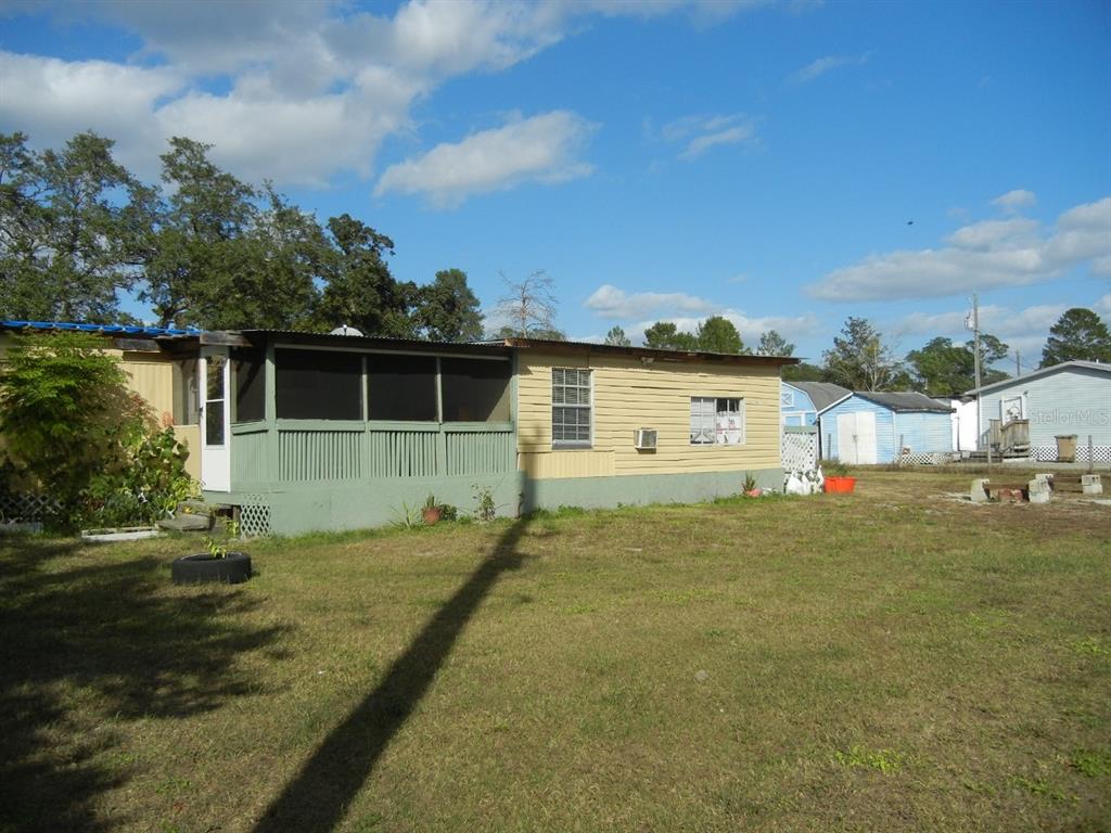 A single-story mobile home with a green screened-in porch sits on a grassy lot — 27945 VEVA AVENUE, PAISLEY, FL