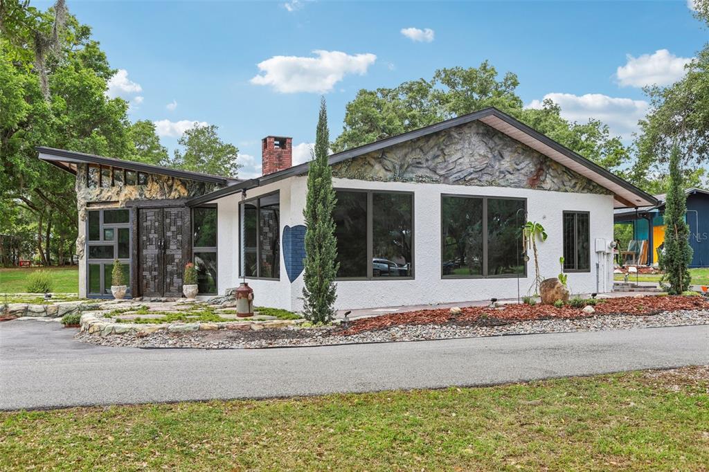 A single-story house with white stucco walls, rock accents, and a brick chimney — 27616 MILLER ROAD, DADE CITY, FL