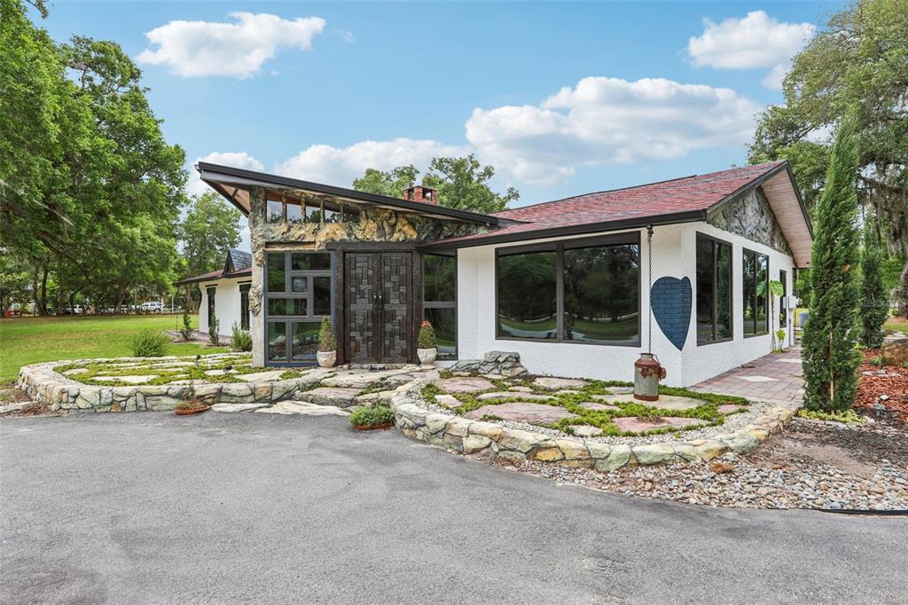 A modern house with a stone facade, slanted roof, and landscaped stone garden beds — 27616 MILLER ROAD, DADE CITY, FL