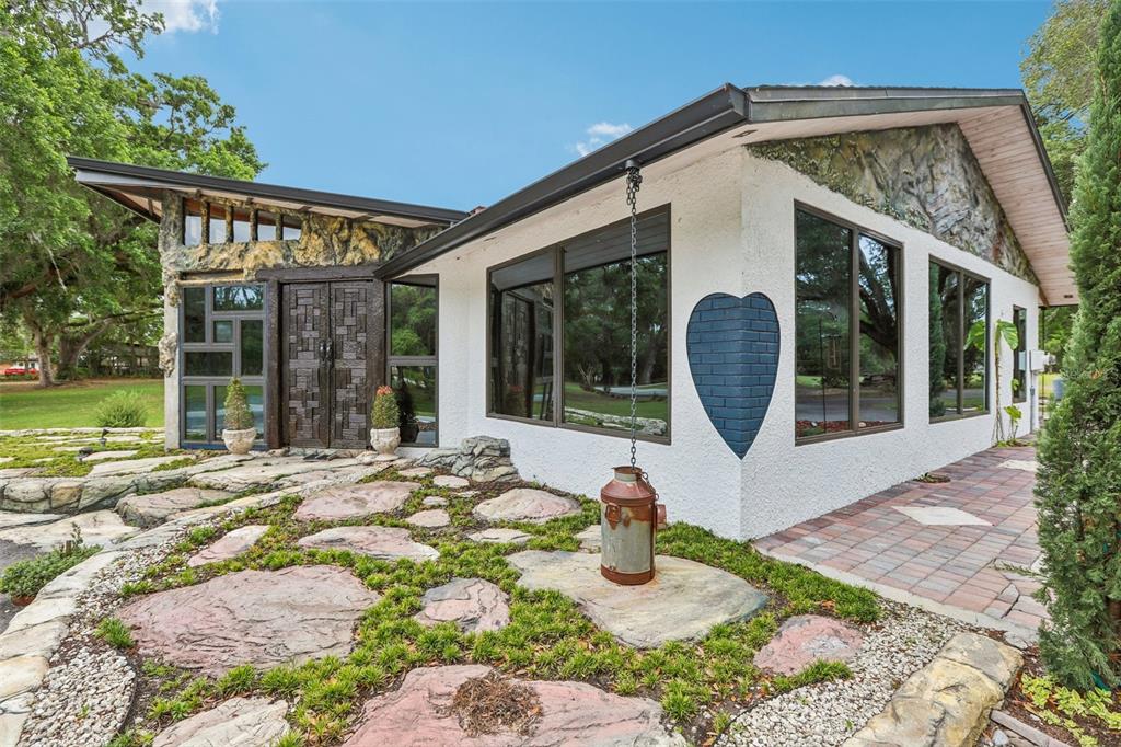 The exterior of a modern home features a stone-accented facade, large windows, and landscaped grounds — 27616 MILLER ROAD, DADE CITY, FL