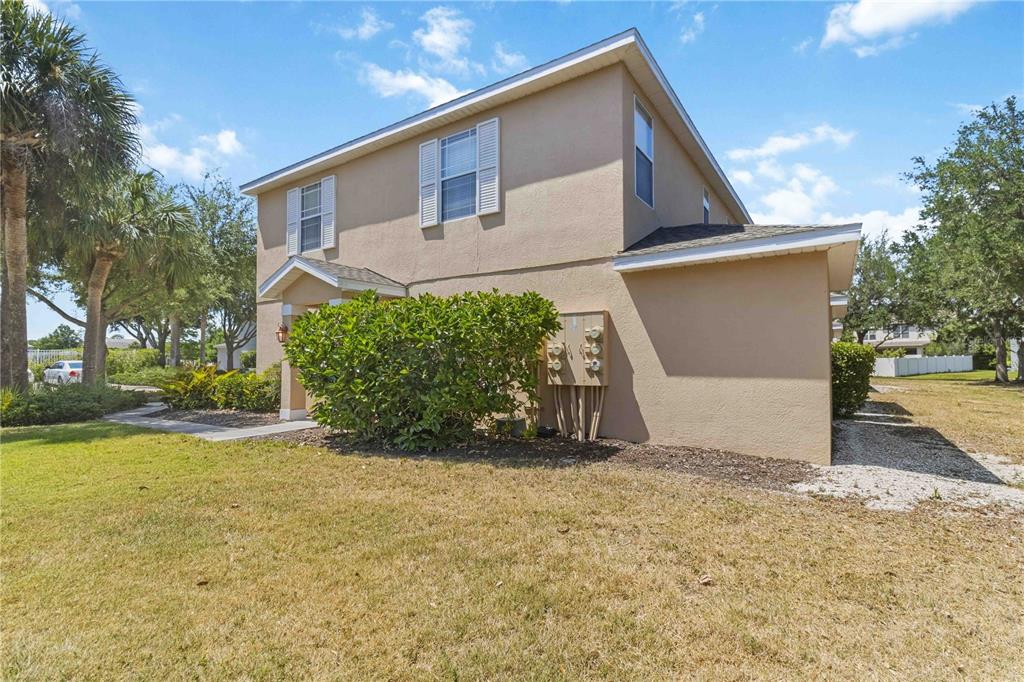 A two-story tan stucco house with a front entrance, landscaping, and exterior utility meters — 14969 AMBERJACK TERRACE UNIT 14969, BRADENTON, FL