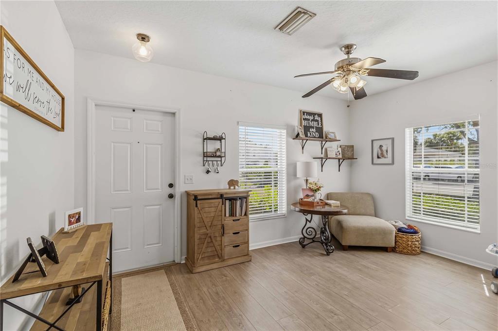 A bright entryway features wood-look flooring, a white front door, and a small sitting area — 14969 AMBERJACK TERRACE UNIT 14969, BRADENTON, FL