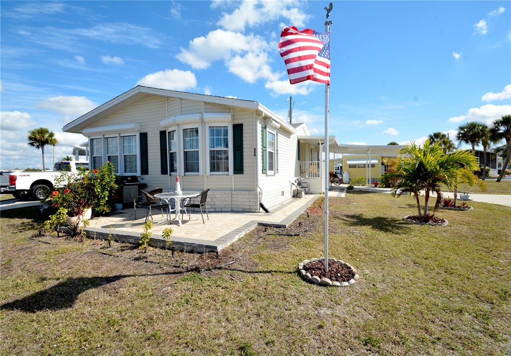 A single-story mobile home features a paved patio, a flagpole, and a carport — 809 S WATERWAY, VENICE, FL