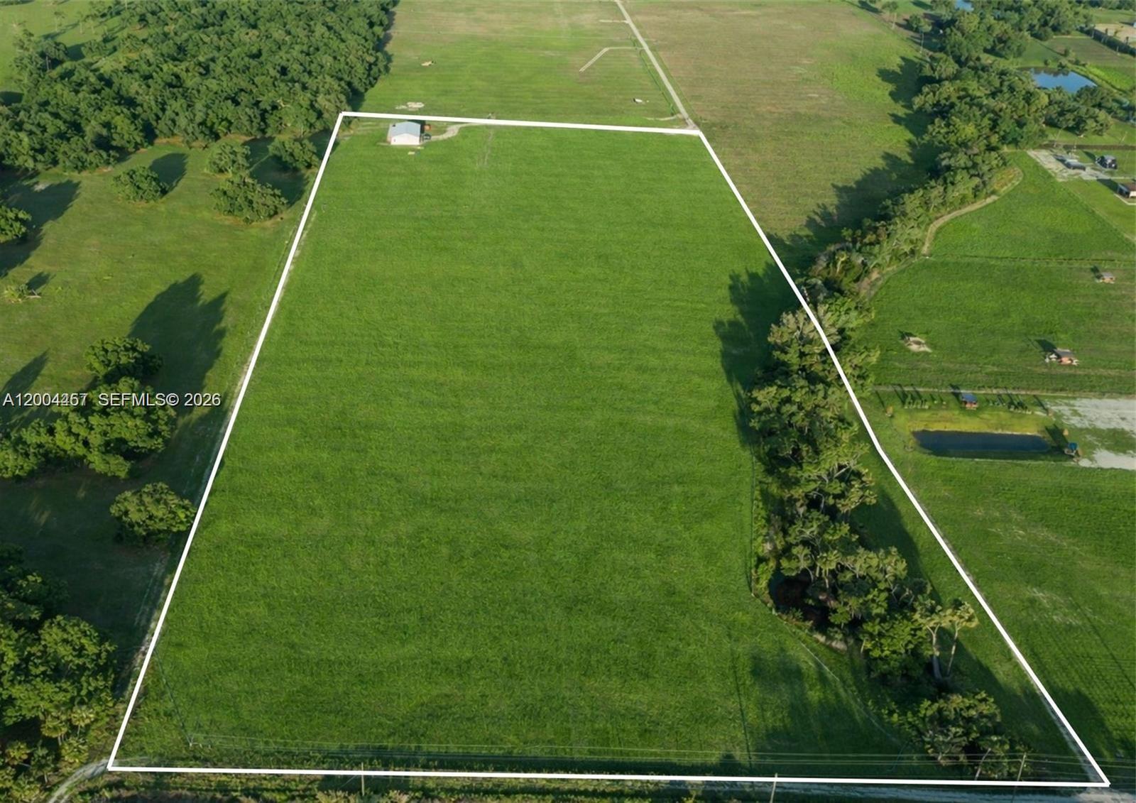 An aerial view shows a large, rectangular grassy lot outlined in white with a small building — 595 Norris Rd, La Belle FL 33935, LA BELLE, FL
