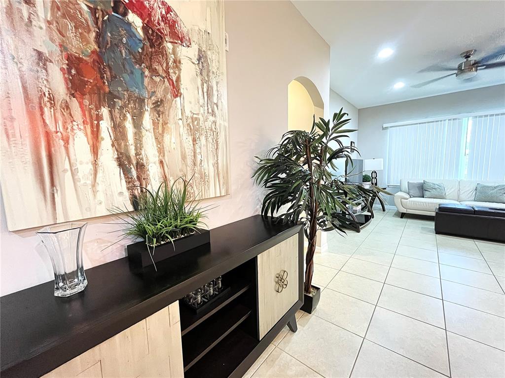A living room features a dark wood console table, a large abstract painting, and tile flooring — 137 NAVIGATION CIRCLE, OSPREY, FL