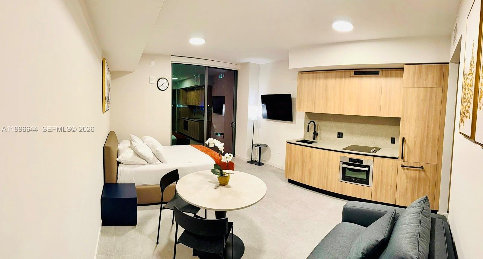 A studio apartment features a kitchenette, a dining table, a bed, and a sofa — 121 NE 5 St # 901B, Miami FL 33132, MIAMI, FL