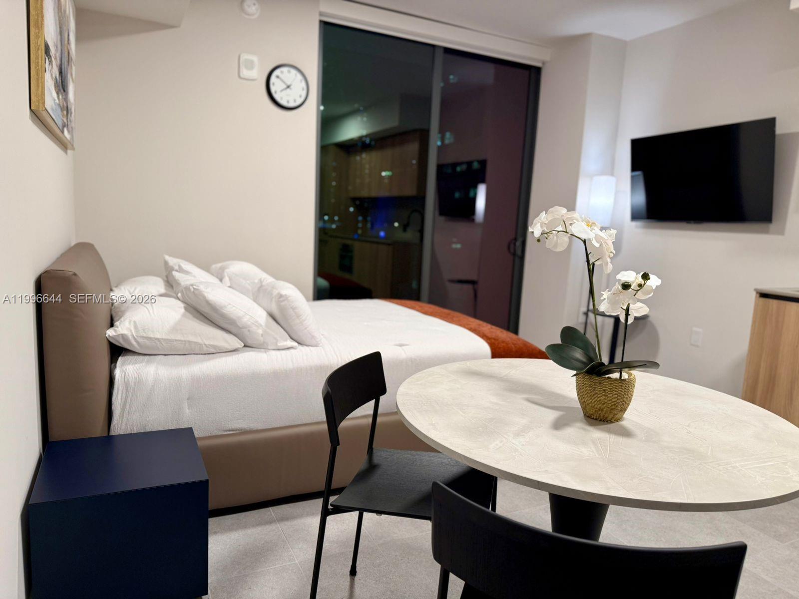 A bedroom features a bed, a small dining table with chairs, and a wall-mounted television — 121 NE 5 St # 901B, Miami FL 33132, MIAMI, FL
