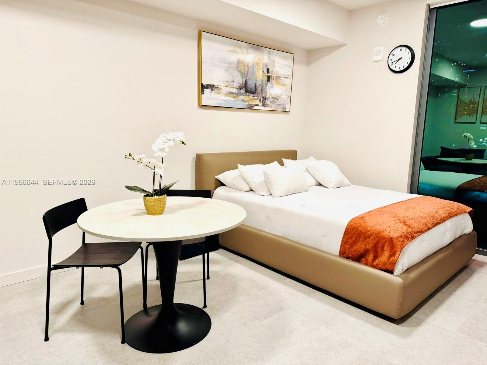 A bedroom features a bed with an orange throw, a round table, and wall art — 121 NE 5 St # 901B, Miami FL 33132, MIAMI, FL