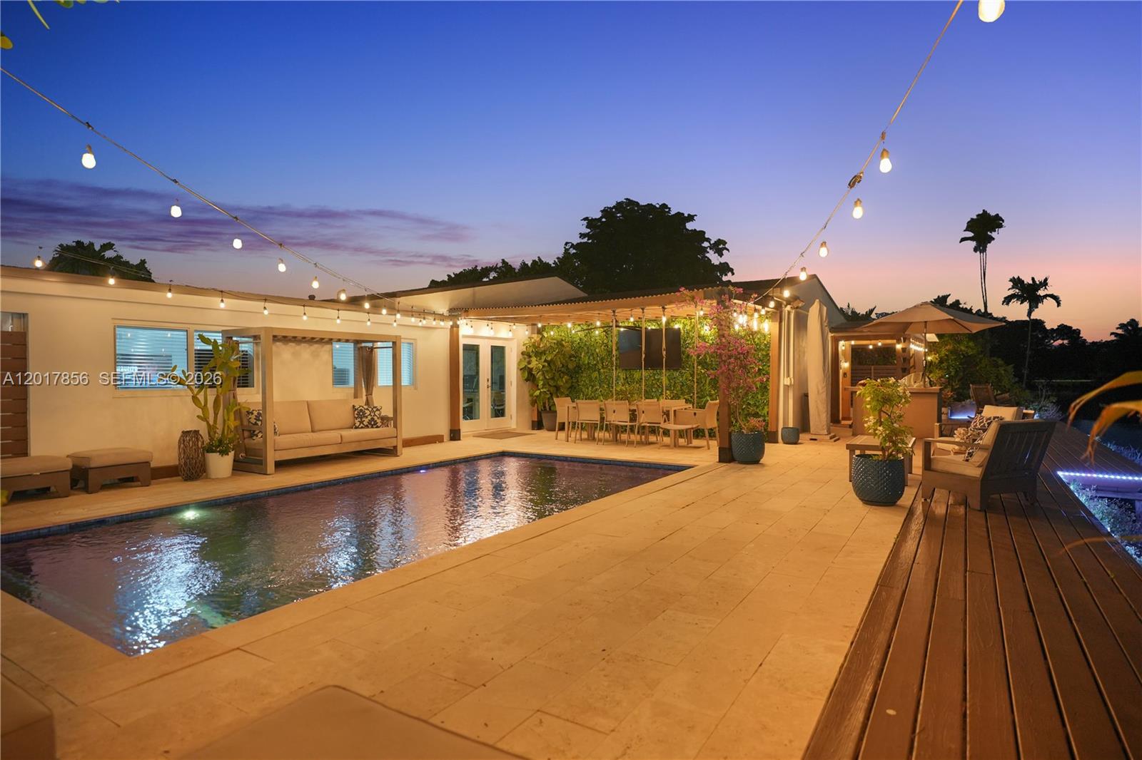 A backyard patio features a swimming pool, outdoor dining area, and string lights at dusk — 5241 SW 104th Ave, Miami FL 33165, MIAMI, FL