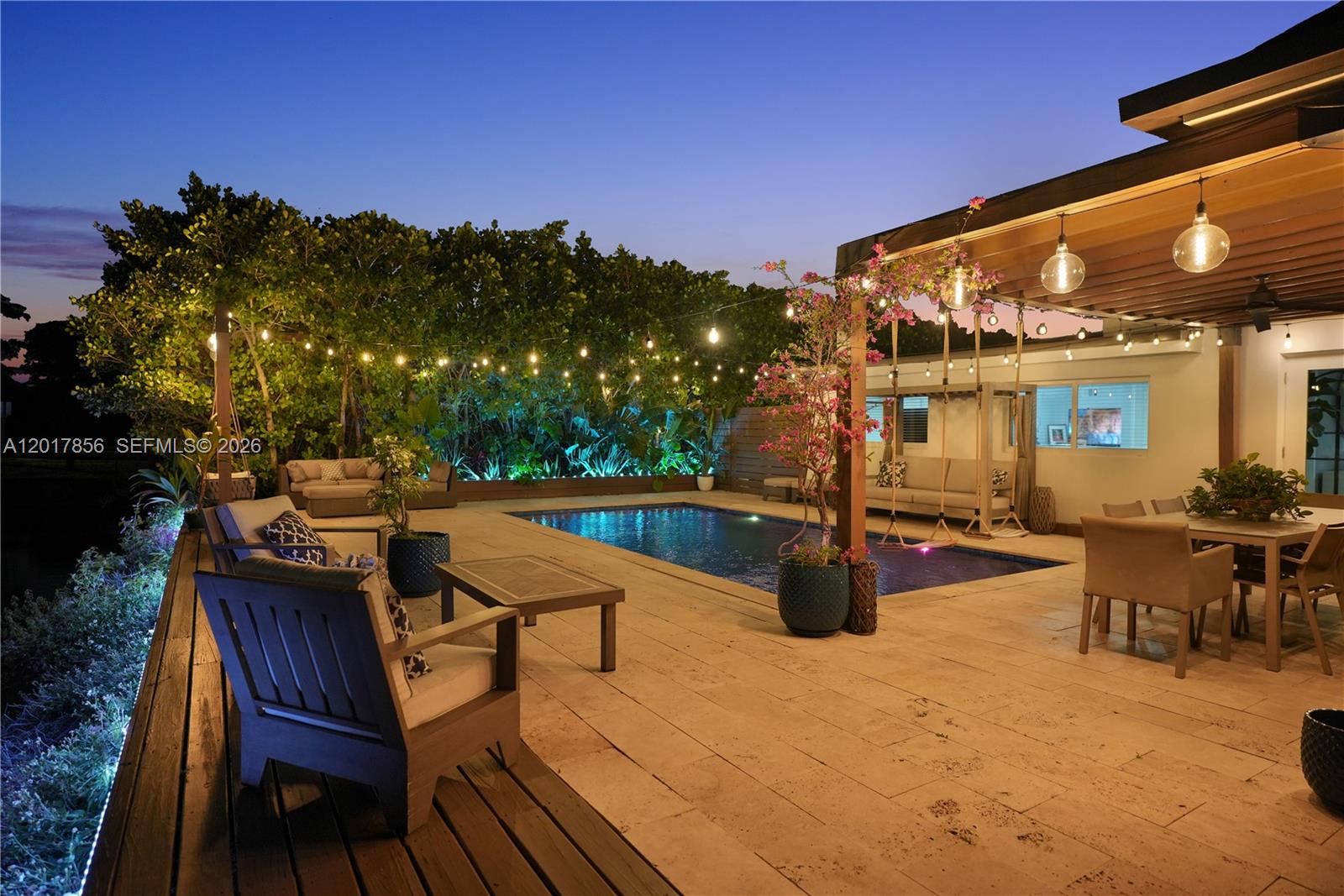An outdoor patio features a swimming pool, lounge seating, dining area, and string lighting at dusk — 5241 SW 104th Ave, Miami FL 33165, MIAMI, FL