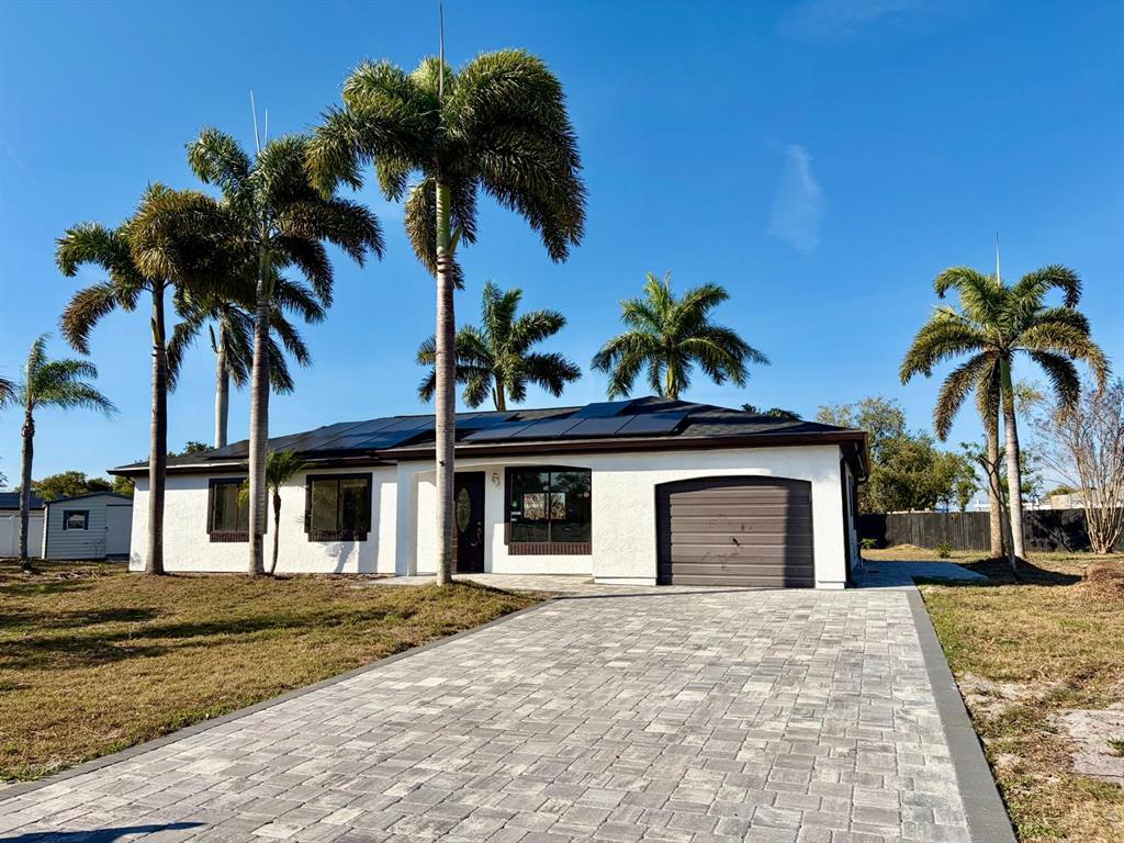 A single-story white house with a paved driveway, solar panels, and several palm trees — 6678 ACMAR COURT, NORTH PORT, FL