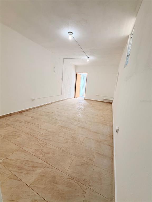 An empty, rectangular room features light-colored tile flooring, white walls, and exposed ceiling wiring — Calle 601 BLOQUE 224 COMERCIAL 3, CAROLINA, PR