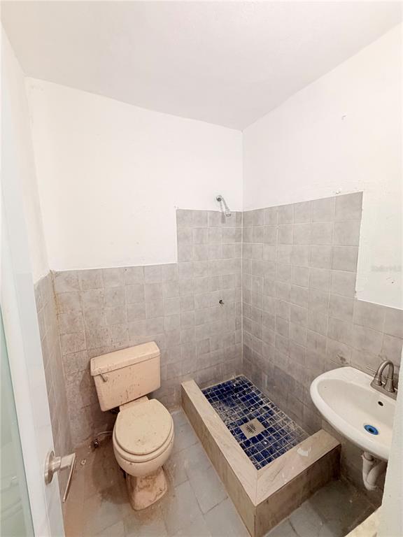 A small bathroom features a toilet, a raised shower stall with blue tiles, and a sink — Calle 601 BLOQUE 224 COMERCIAL 3, CAROLINA, PR
