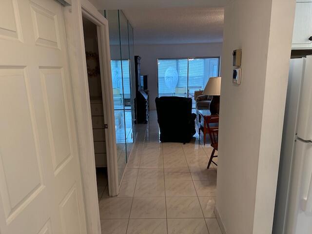A tiled hallway leads from a kitchen area into a living room with mirrored walls — 7705 NW 5th Court # 103, Margate FL 33063, MARGATE, FL