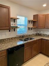A kitchen features wood cabinets, granite countertops, a double sink, and open shelving — 3826 EXETER LANE, LAKELAND, FL