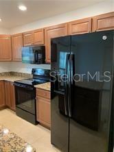 A kitchen features wood cabinets, black appliances, and granite countertops — 3826 EXETER LANE, LAKELAND, FL