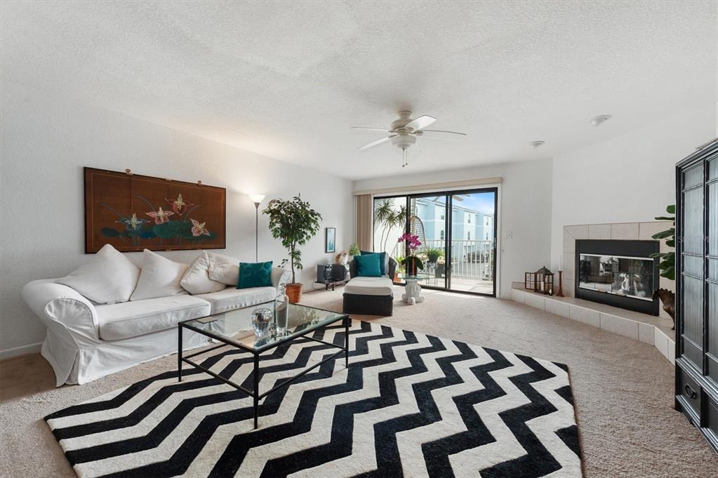 A living room features a white sofa, a chevron rug, and a fireplace — 745 PINELLAS BAYWAY S UNIT 206, ST PETERSBURG, FL