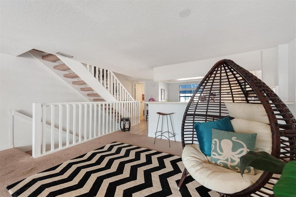 A living area features a hanging egg chair, a chevron rug, and a white staircase — 745 PINELLAS BAYWAY S UNIT 206, ST PETERSBURG, FL