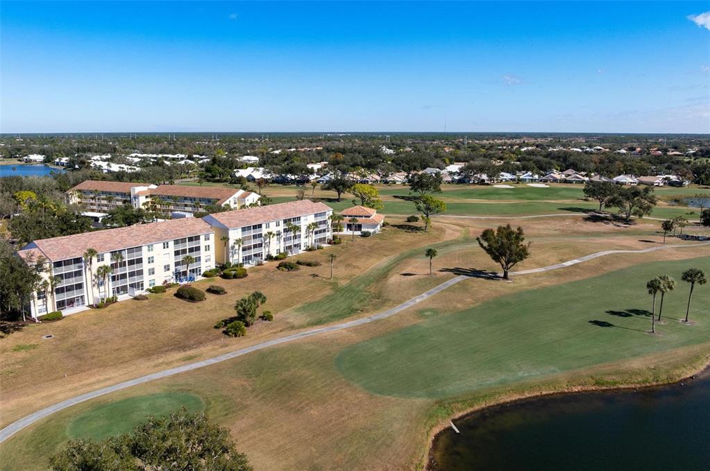 An aerial view shows a multi-story apartment building situated next to a golf course — 918 WEXFORD BOULEVARD UNIT 918, VENICE, FL