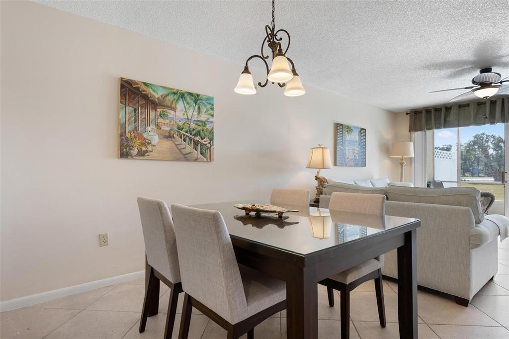 A dining area with a glass-topped table, four chairs, and a chandelier under a ceiling fan — 918 WEXFORD BOULEVARD UNIT 918, VENICE, FL