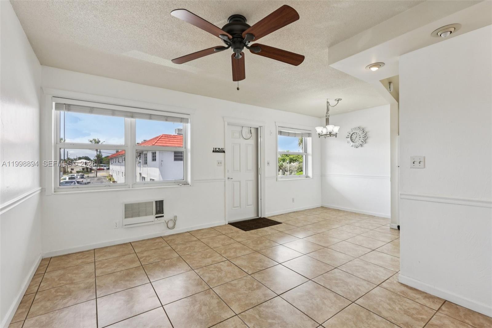 An empty room features tile flooring, a ceiling fan, and a white front door — 22 SE 3rd Ter # 18, Dania Beach FL 33004, DANIA BEACH, FL