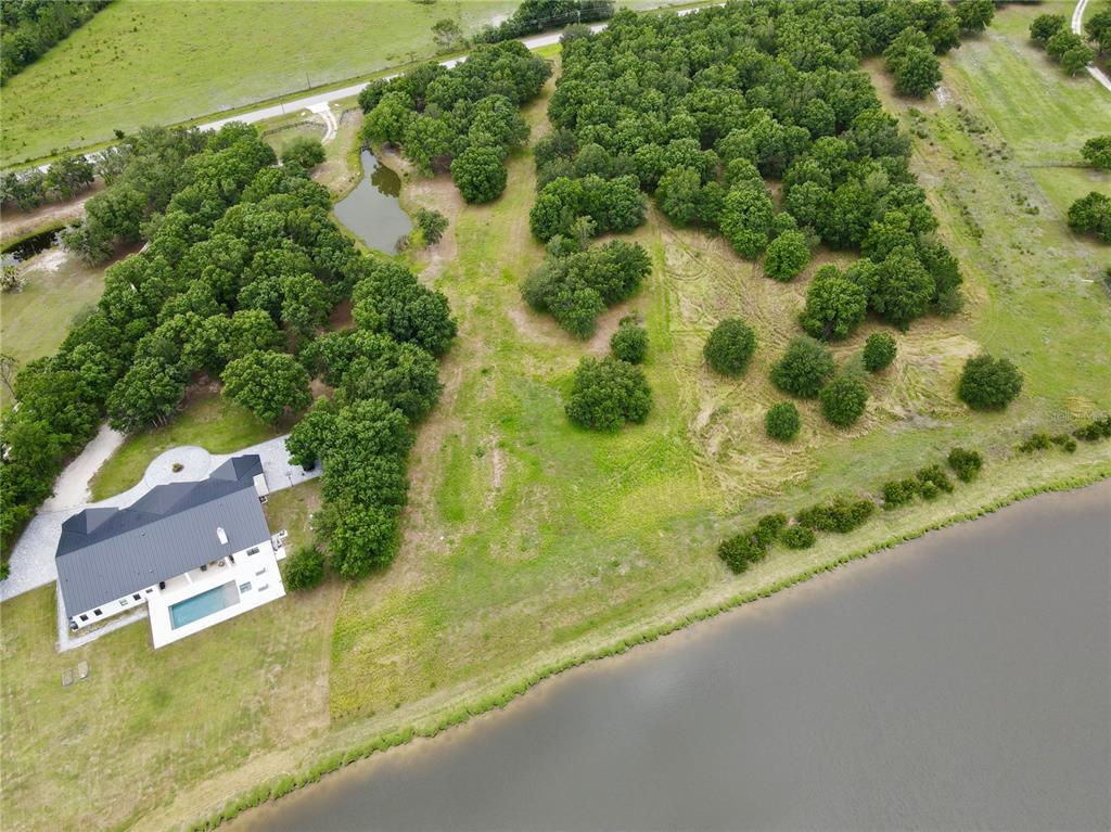 An aerial view shows a house with a pool, a pond, and surrounding wooded land — 4946 WAUCHULA RD, MYAKKA CITY, FL