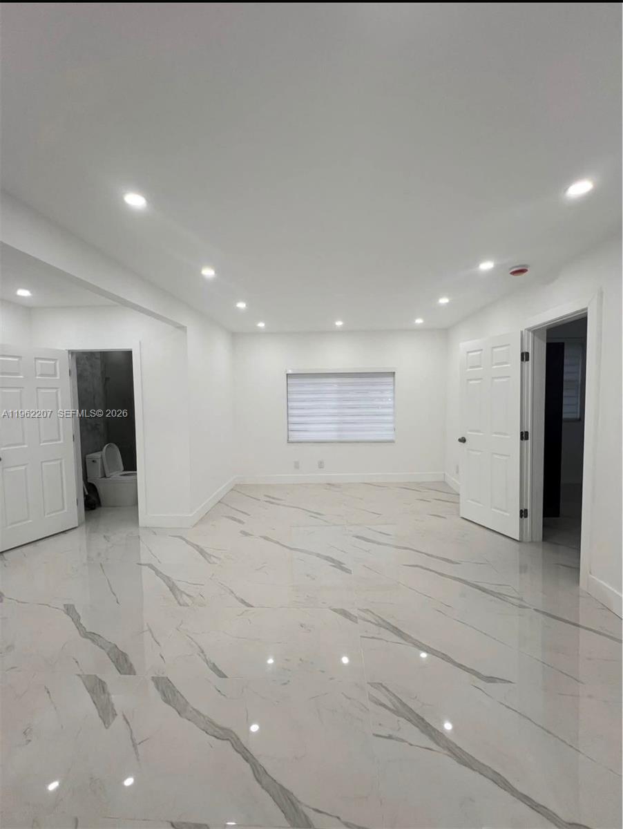A bright, empty room features white marble-look tile flooring, recessed lighting, and two doorways — 1015 S 17th Ave # 8, Hollywood FL 33020, HOLLYWOOD, FL