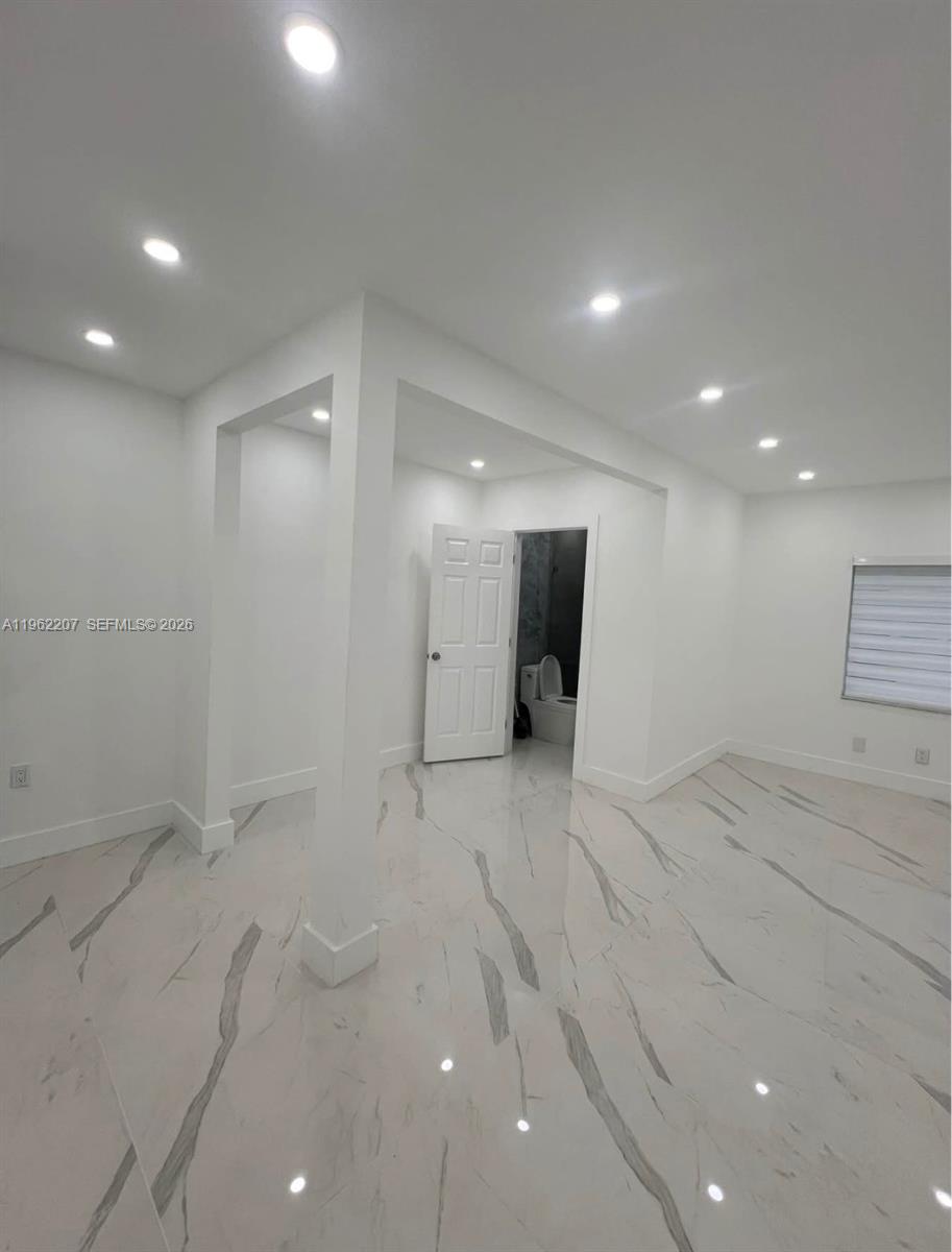 A bright, minimalist room features white walls, recessed ceiling lights, and polished marble-patterned tile flooring — 1015 S 17th Ave # 8, Hollywood FL 33020, HOLLYWOOD, FL