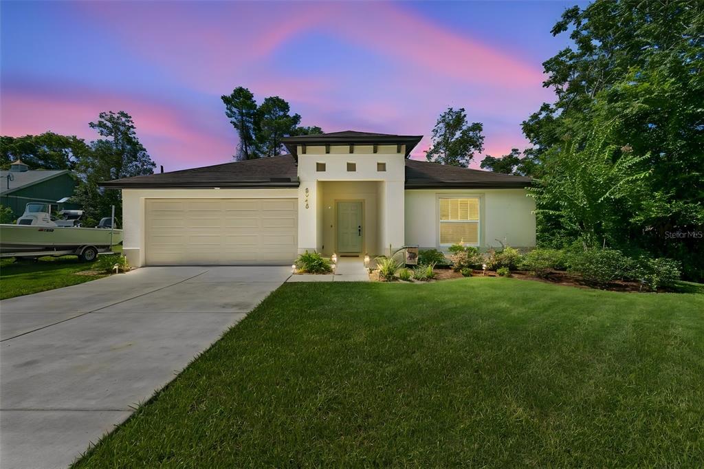 A single-story house with a white stucco facade, a two-car garage, and a green lawn — 8948 CARRIE WAY, WEEKI WACHEE, FL