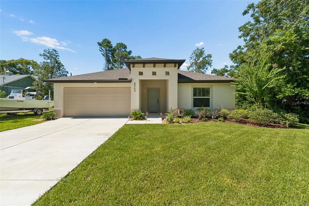 A single-story house with a beige exterior, a two-car garage, and a front lawn — 8948 CARRIE WAY, WEEKI WACHEE, FL