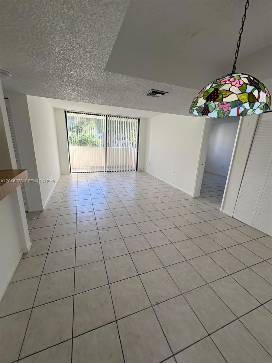 A tiled living area features a stained-glass pendant light and sliding glass doors to a balcony — 8004 SW 149th Ave # C205, Miami FL 33193, MIAMI, FL