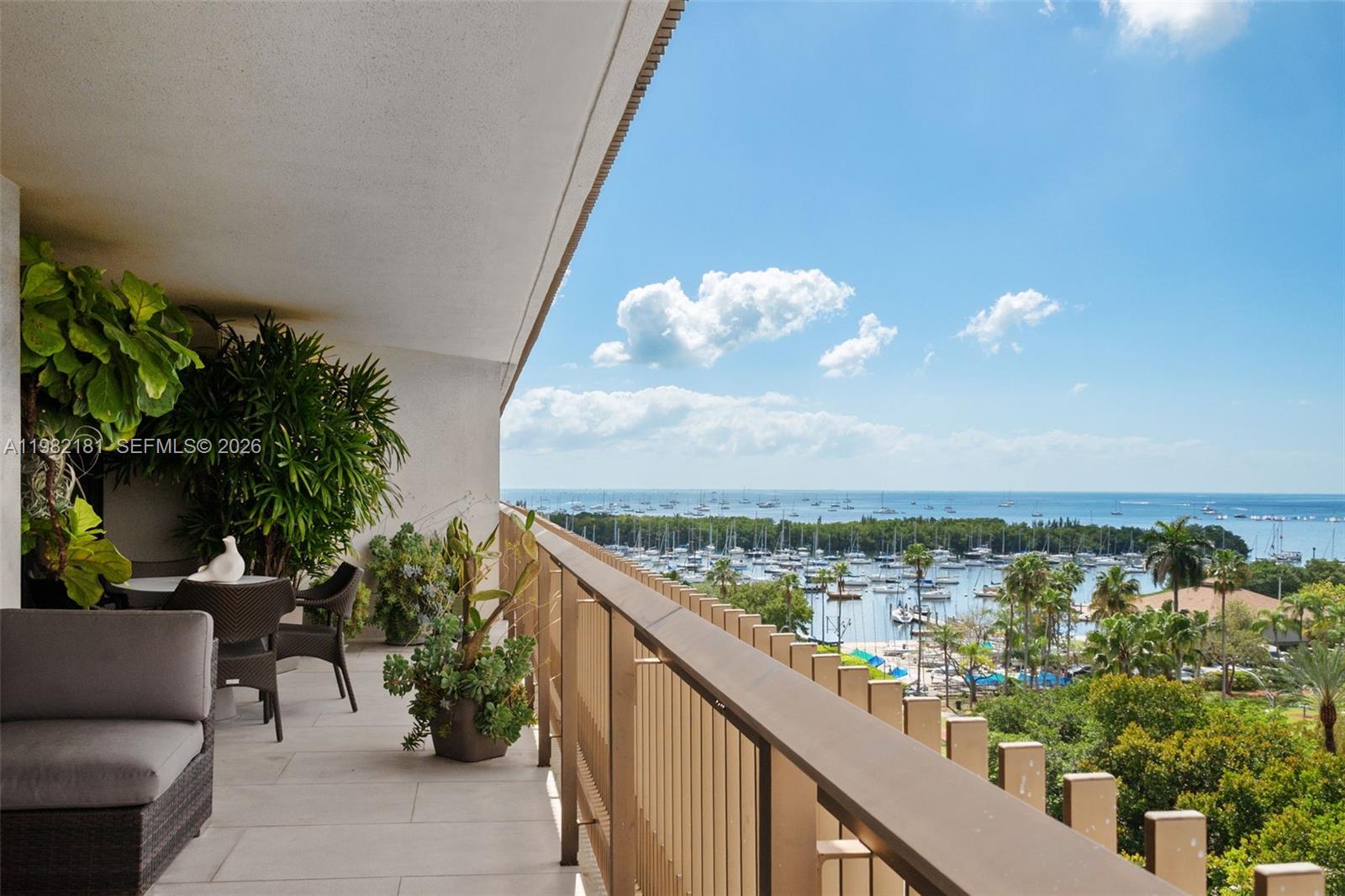 A balcony with outdoor seating and potted plants overlooks a marina and the ocean — 2901 S Bayshore Dr # 8E, Coconut Grove FL 33133, COCONUT GROVE, FL