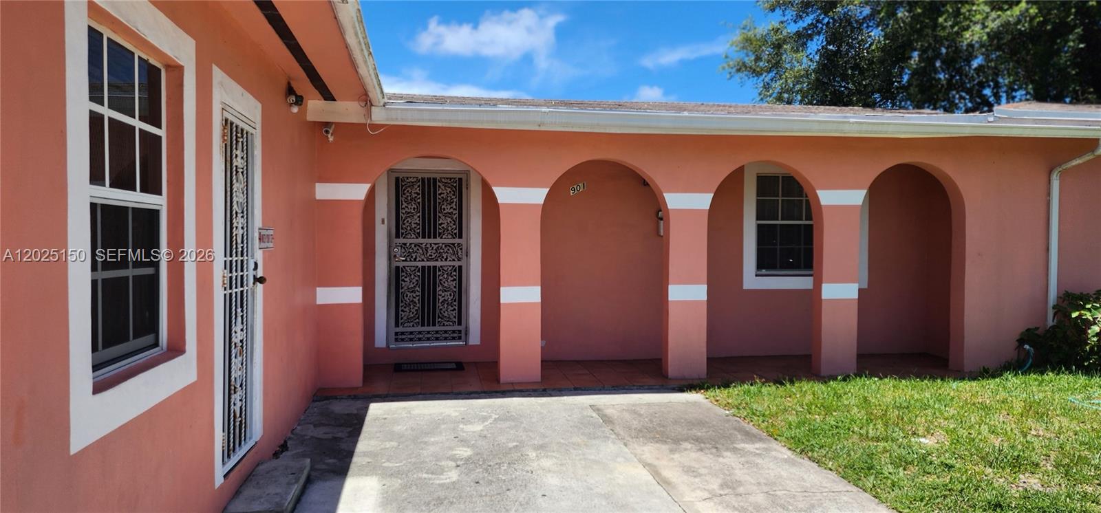 The exterior of a peach-colored house features a covered porch with multiple arched openings — 901 NE 160th Ter, North Miami Beach FL 33162, NORTH MIAMI BEACH, FL
