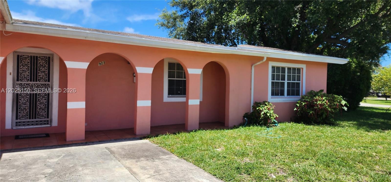 The exterior of a peach-colored house features a covered porch with three arched openings — 901 NE 160th Ter, North Miami Beach FL 33162, NORTH MIAMI BEACH, FL