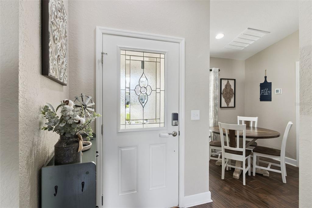 A white front door with a glass insert opens into a dining area with wood floors — 925 LOCHLAND LOOP, BARTOW, FL