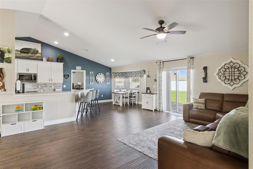 An open-concept living area features a kitchen with a blue accent wall and wood-look flooring — 925 LOCHLAND LOOP, BARTOW, FL