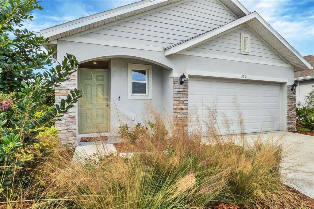 A single-story house exterior features a light green front door, stone accents, and a garage — 3293 HILLTOP CIRCLE, BRADENTON, FL