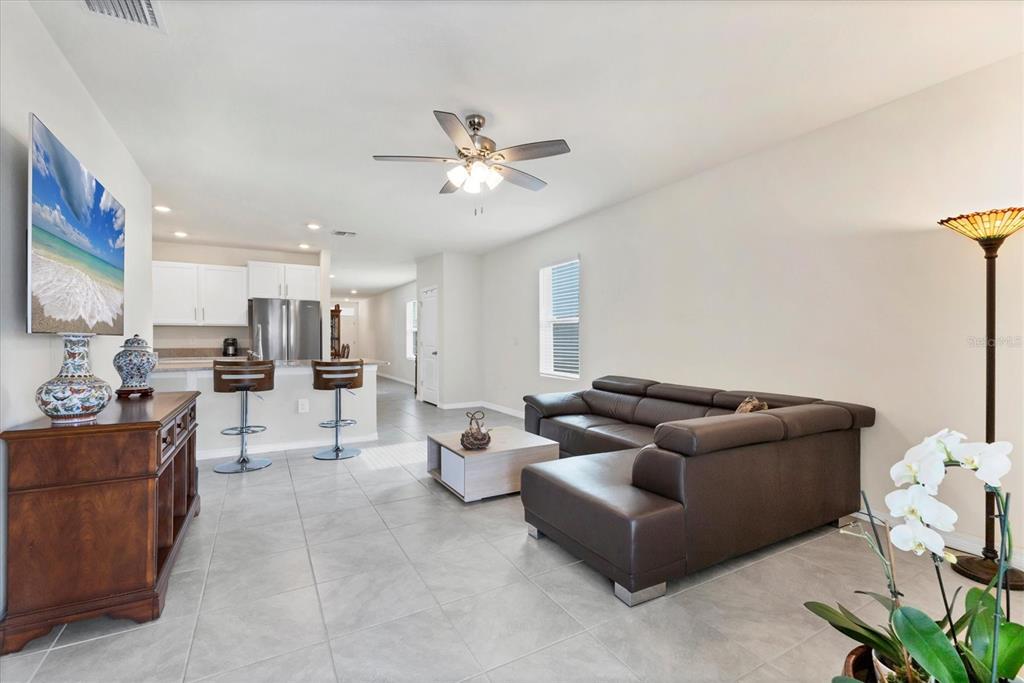 A living room with tile floors, a brown sectional sofa, and an open kitchen area — 3293 HILLTOP CIRCLE, BRADENTON, FL