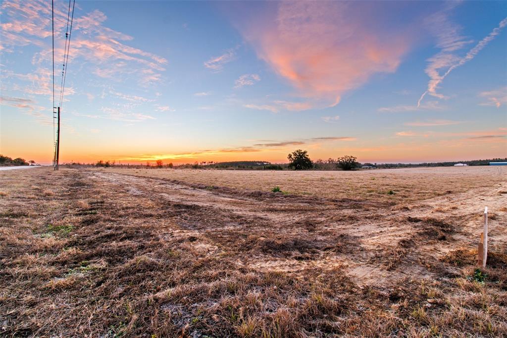 A wide, flat, grassy field under a sunset sky with utility poles on the left — 4302 ROYAL SKY (LOT 4) COURT, BROOKSVILLE, FL