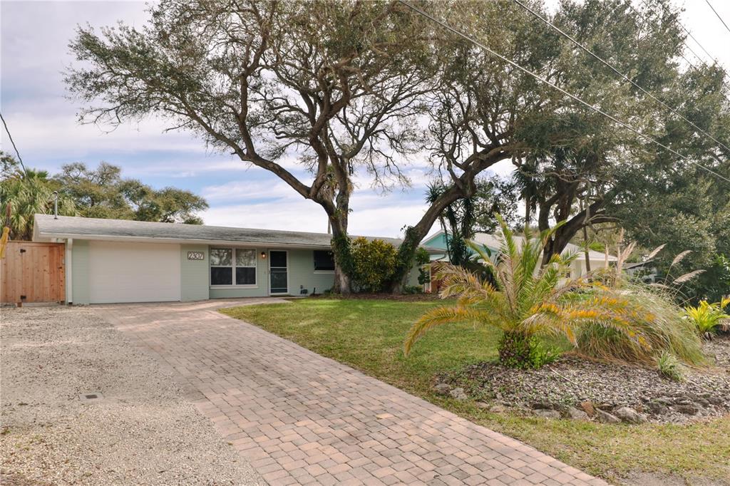 A single-story house with a paved driveway, a garage, and large trees in the yard — 2307 SAXON DRIVE, NEW SMYRNA BEACH, FL