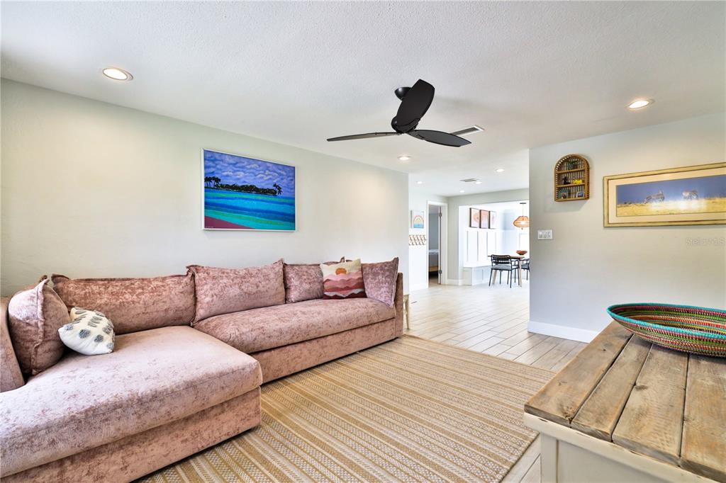 A living room features a pink sectional sofa, a striped rug, and a ceiling fan — 2307 SAXON DRIVE, NEW SMYRNA BEACH, FL