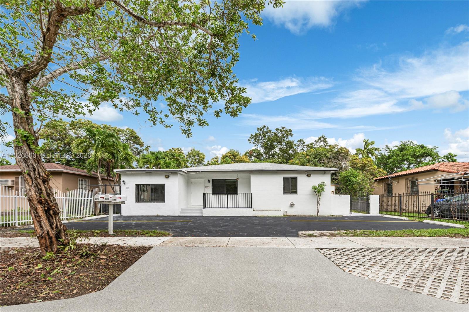 A white, single-story house features a black metal railing and a paved driveway — 821 NW 36th Ave, Miami FL 33125, MIAMI, FL