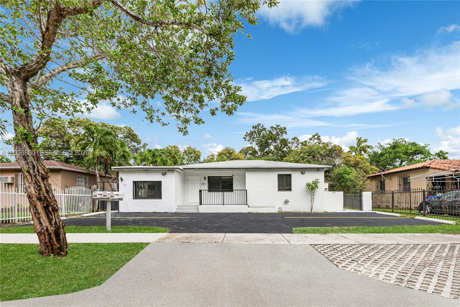 A white, single-story house with a black asphalt driveway and a metal railing entrance — 821 NW 36th Ave, Miami FL 33125, MIAMI, FL