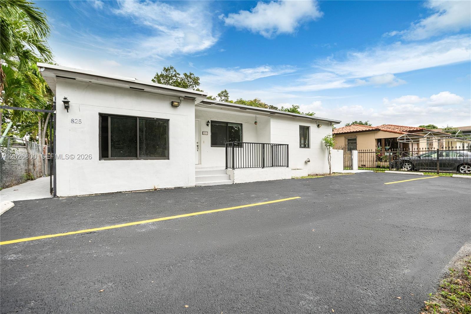 A white, single-story building features a black-railed entrance and a paved parking lot — 821 NW 36th Ave, Miami FL 33125, MIAMI, FL