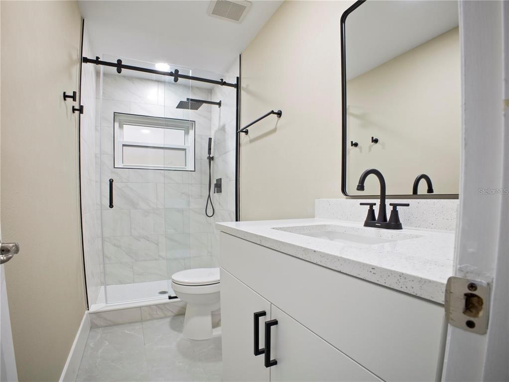 A modern bathroom features a white vanity, a glass-enclosed shower, and black hardware — 196 W LAKE DAMON DRIVE, AVON PARK, FL