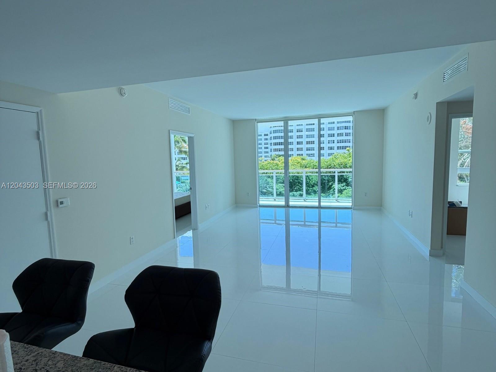 A bright, empty living area features white tile floors, large glass balcony doors, and neutral walls — 951 Brickell Ave # 1206, Miami FL 33131, MIAMI, FL